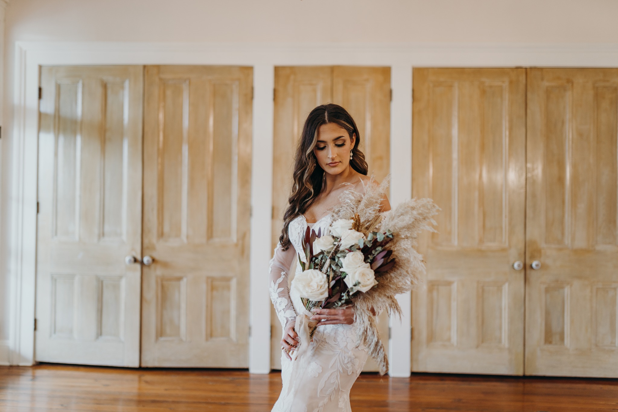 Bride in gown standing at window in bridal suite at Maison De Tours historic venue Saint Martinville Louisiana